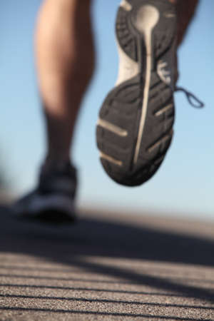 Unfocused man shoes running on the asphalt with the sky in the backgroundの写真素材