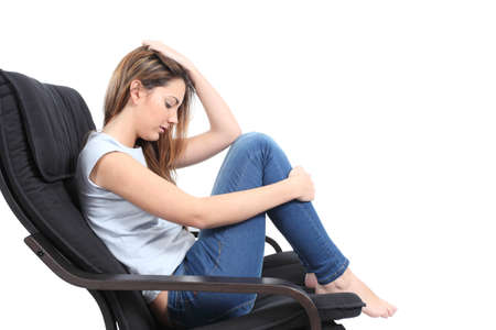 Beautiful teenager worried sitting on an armchair in a white isolated background               の写真素材