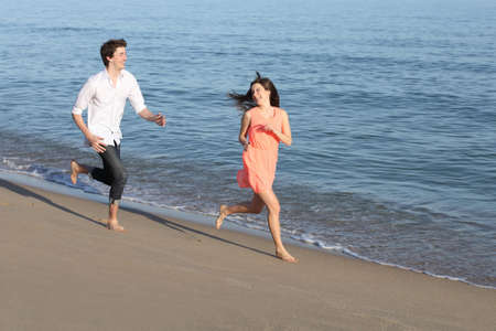 Couple of teenagers running and flirting on the beach shore near the water               の写真素材