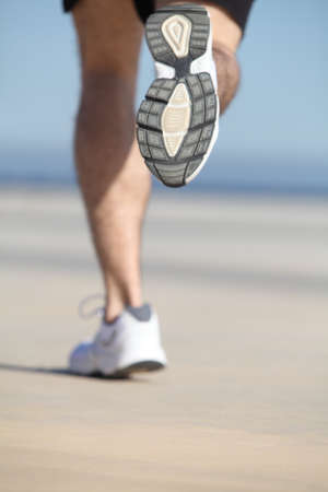 Back view of an unfocused legs of a man running on the concrete of a seafront with the sky in the backgroundの写真素材