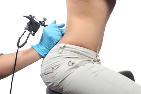 Hands with gloves making a tattoo on a womans lumbar isolated on a white backgroundの写真素材