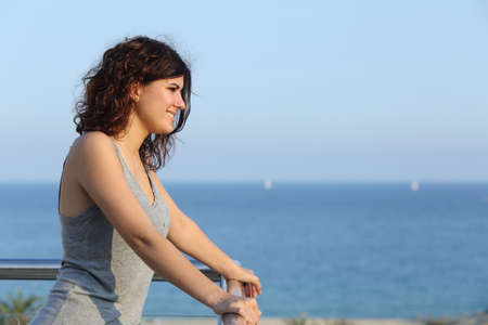 Attractive woman looking ahead from a balcony with the sea in the backgroundの写真素材