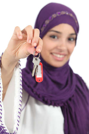 Close up of a beautiful arab woman holding a home keys isolated on a white background            の写真素材