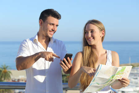 Couple discussing map or smartphone gps on vacations with the sea in the backgroundの写真素材