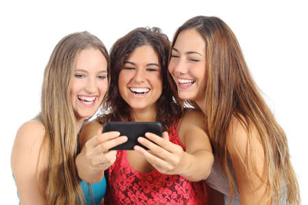 Group of three teenager girls laughing looking the smart phone isolated on a white backgroundの写真素材