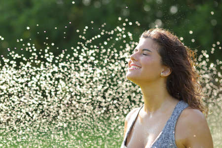 Beautiful woman breathing under a water jet with thousands of drops in the backgroundの写真素材