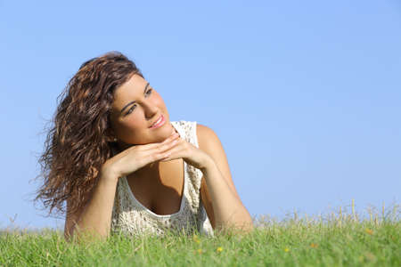 Portrait of a beautiful woman lying on the grass with a blue sky in the background            の写真素材