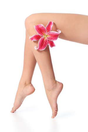 Smooth and waxed perfect woman legs with a flower isolated on a white background             の写真素材