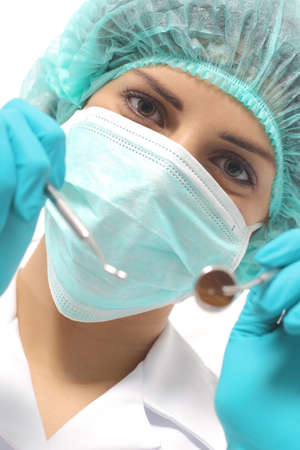 Close up of a dentist woman with a mask holding tools ready to operate isolated on a white backgroundの写真素材