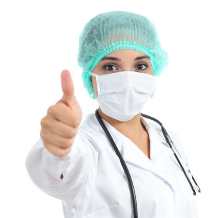 Female doctor with a surgical mask with thumb up isolated on a white background           の写真素材