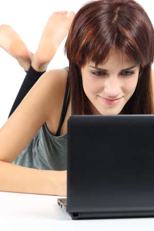 Beautiful woman lying and watching a netbook computer isolated on a white backgroundの写真素材