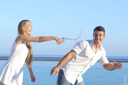 Woman throwing water to her boyfriend with the sky in the backgroundの写真素材