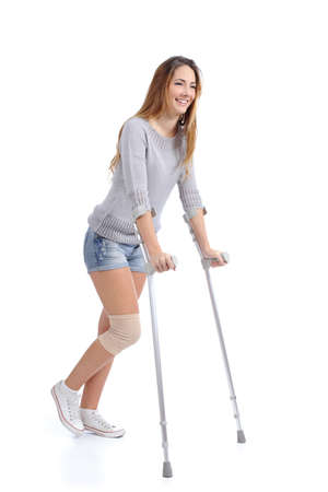 Beautiful woman smiling and hobbling with crutches isolated on a white background          の写真素材