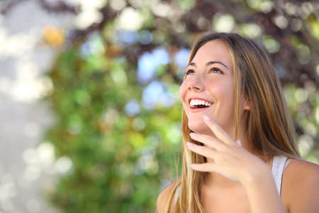 Beautiful woman laughing and looking above with a green background copy space              の写真素材