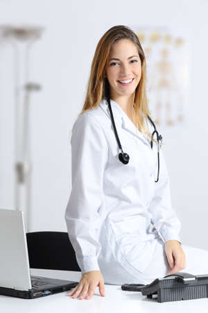 Beautiful female doctor sitting on the desk of her consultationの写真素材
