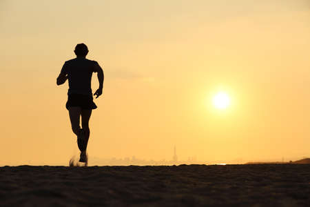 Back view of a man running on the beach at sunset with the horizon in the backgroundの写真素材