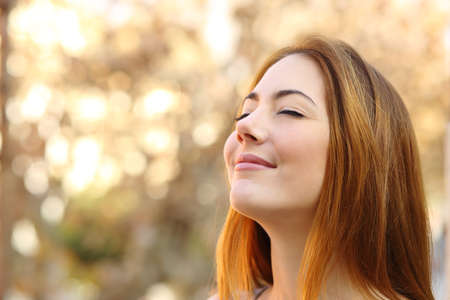 Portrait of a beautiful woman doing breath exercises with an autumn unfocused backgroundの写真素材