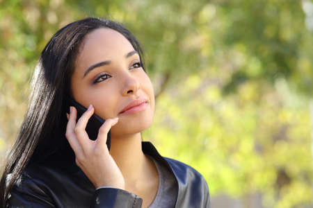 Arab business woman on the mobile phone in a park with a green backgroundの写真素材