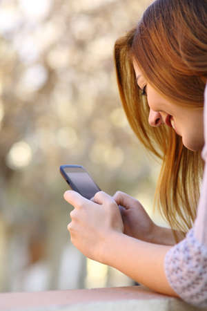 Close up of a happy woman using a smart phone with a warmth backgroundの写真素材