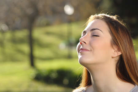 Portrait of a relaxed woman breathing deep in a park with a warmth background and backlitの写真素材