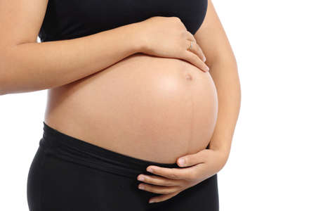 Close up of a belly of a pregnant woman with the hands touching it isolated on a white backgroundの写真素材