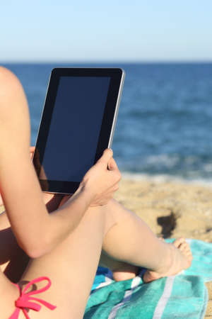 Woman on vacations reading a tablet on the beach with the horizon in the background                 の写真素材