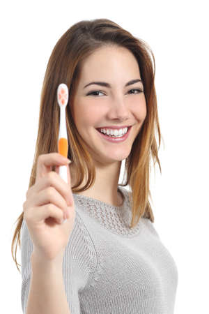 Woman portrait with a perfect white smile holding a toothbrush isolated on a white backgroundの写真素材