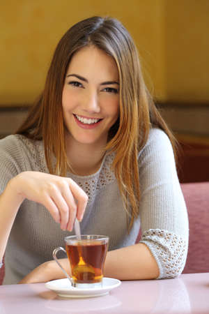 Happy woman in a coffee shop with a cup of tea with a warmth background            の写真素材