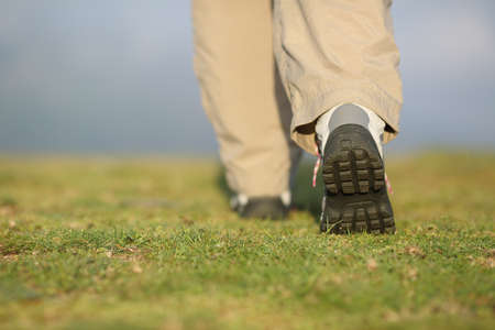 Back view of hiker legs with boots walking on the mountain with an unfocused 