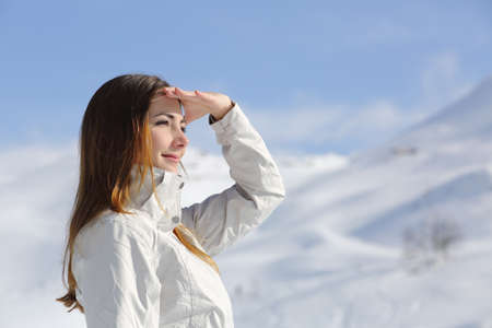 Hiker woman looking forward in the snowy mountain with her hand on foreheadの写真素材