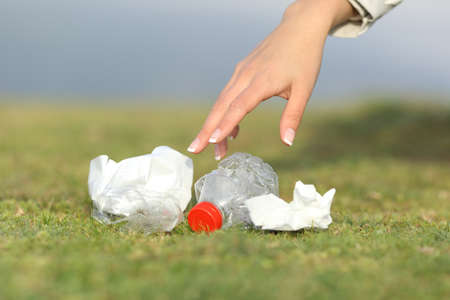 Woman hand collecting garbage of the grass in the mountain with copy spaceの写真素材