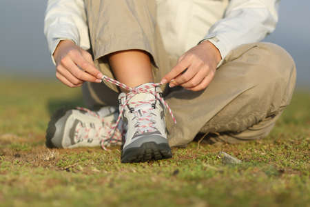 Hiker woman tying shoelaces of boots with an unfocused backgroundの写真素材