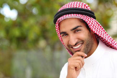 Portrait of a handsome arab saudi emirates man with a white smile and a green backgroundの写真素材