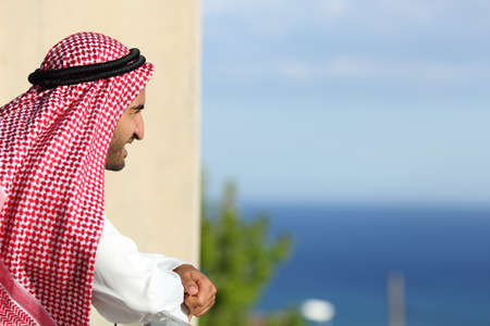 Happy relaxed arab saudi man looking the sea from a balcony of an hotelの写真素材