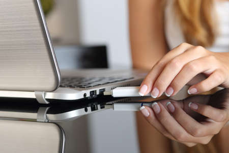 Close up of a woman hand plugging an usb  pendrive on a laptop at homeの写真素材