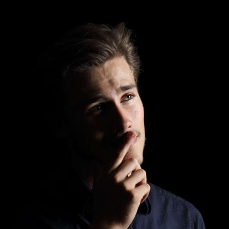 Attractive man thinking an idea isolated on a black background