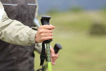 Hiker hands holding a hiking pole while walking with a green backgroundの写真素材