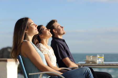 Group of friends breathing fresh air in a restaurant on the beach with the ocean in the backgroundの写真素材