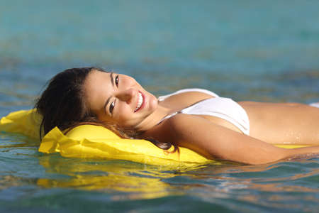 Tourist woman bathing in a tropical sea floating on an inflatable bed and enjoying summer holidaysの写真素材