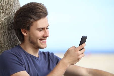 Young teenager boy sharing social media in a smart phone with the sky in the background