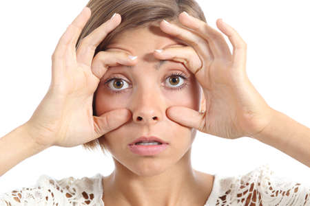 Tired woman opening her eyes with the fingers isolated on a white backgroundの写真素材