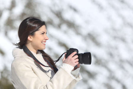 Tourist woman photographing on winter holidays with a snowy mountain in the backgroundの写真素材