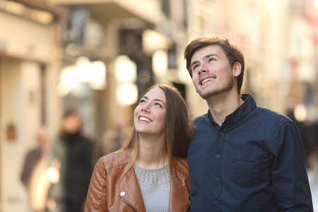 Couple walking and looking above in the street of a cityの写真素材