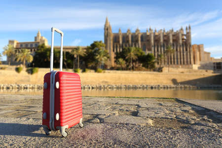 Tourist concept with a suit case in a touristic place with a cathedral in the backgroundの写真素材