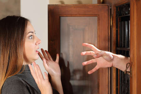 Aggression when a burglar try to attack a housewife with a hand through the door at home