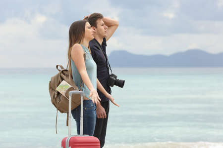Tourists frustrated with the bad weather when arrive to the beach with the cloudy sky in the backgroundの写真素材