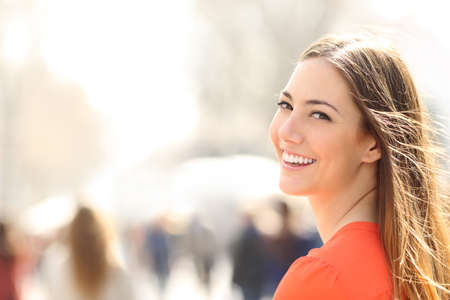 Beauty woman with perfect smile and white teeth walking on the street and looking at camera