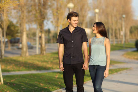 Happy couple laughing while taking a walk in a park