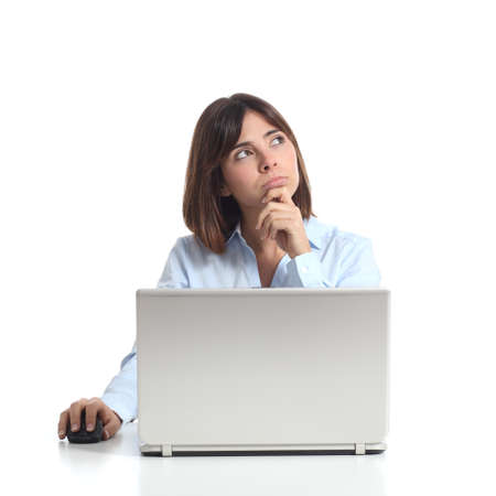 Pensive woman thinking while is using a laptop and looking sideways isolated on a white backgroundの写真素材