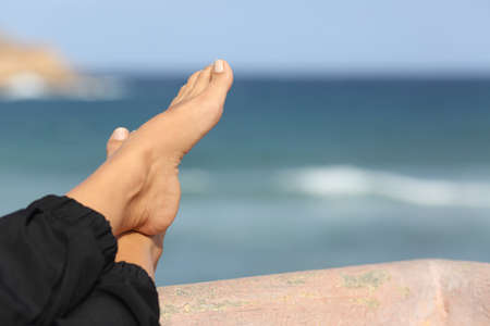 Close up of a woman feet relaxing on an hotel beach terrace with the sea in the backgroundの写真素材